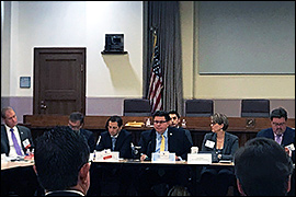 Texas Secretary of State Rolando Pablos sitting with other officials inside a conference room.
