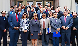 Secretary Hughs posing for a photo with other TBAT members in front of a building. 