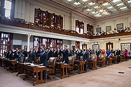 Group of people in a room raising their right arms.